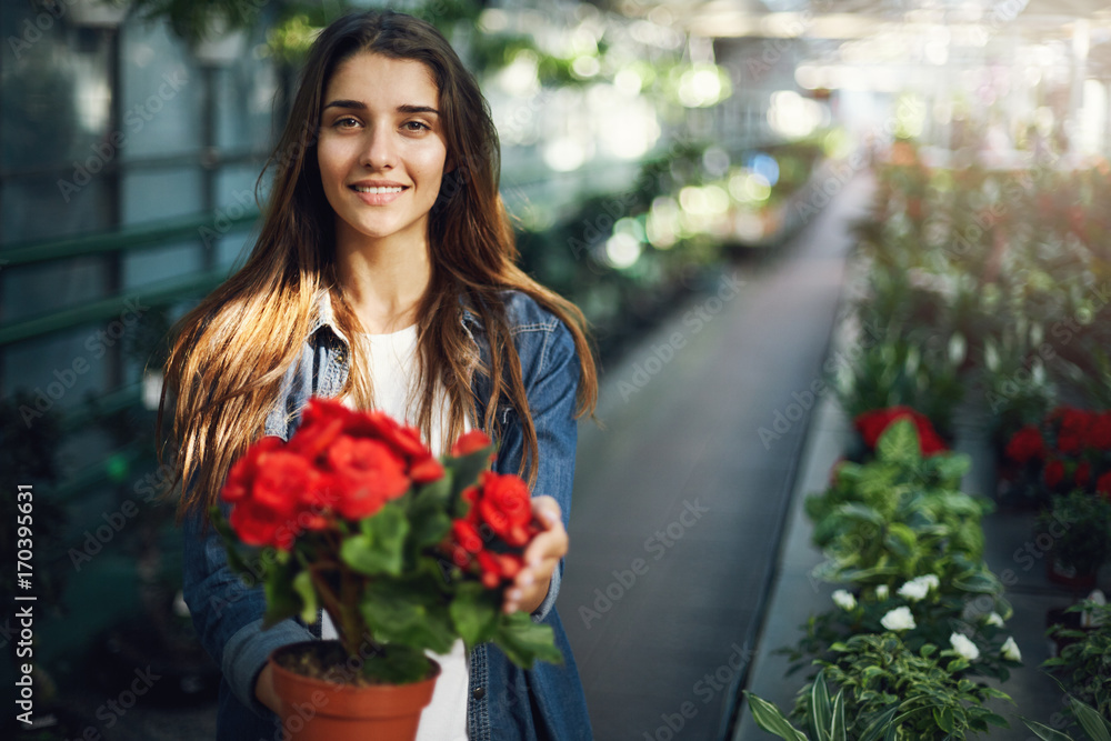 Beautiful female gardener taking care of flowers looking at camera smiling.