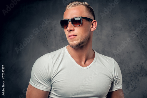 Handsome blond male posing over grey background in a studio. © Fxquadro