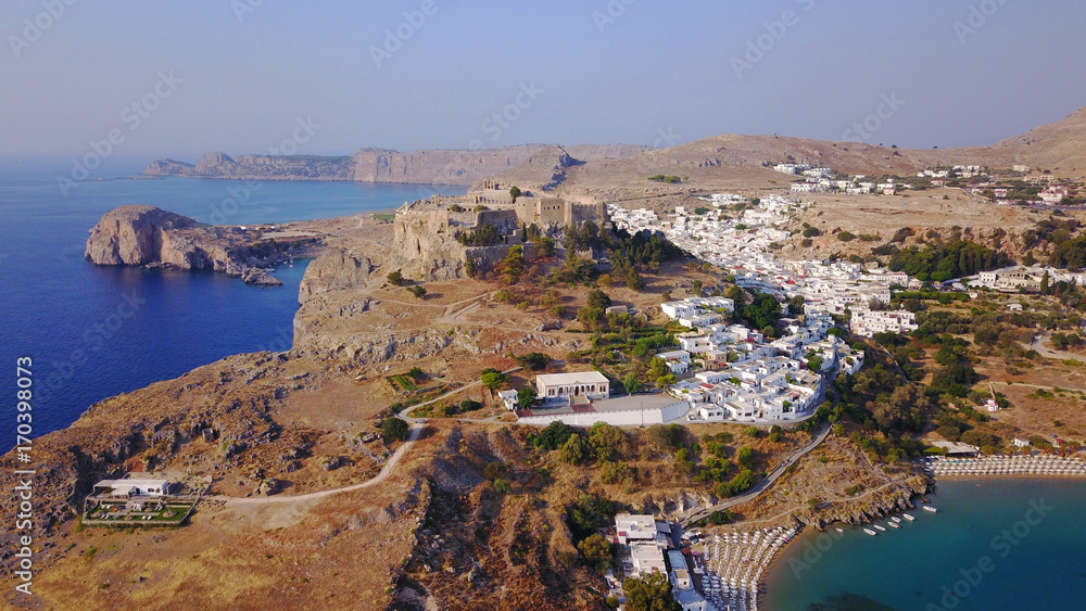 Obraz premium Aerial drone photo of famous beach of Lindos with turquoise waters and iconic ancient Acropolis - village of Lindos, Rodos island, Aegean, Dodecanese, Greece