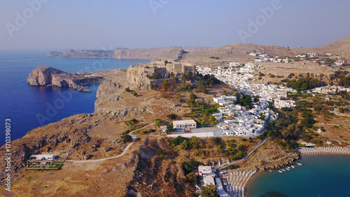 Aerial drone photo of famous beach of Lindos with turquoise waters and iconic ancient Acropolis - village of Lindos, Rodos island, Aegean, Dodecanese, Greece