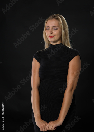 Young wistful woman portrait of a confident businesswoman showing by hands on a black background. Ideal for banners, registration forms, presentation, landings, presenting concept