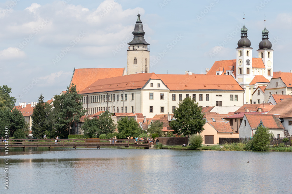 Telc, Czech Republic - August 18, 2017: panoramic view of the church of St. James and the tower of the castle reflected in the pond that surrounds them