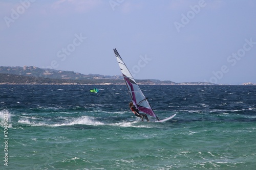 Windsurfing girl planing over the blue choppy sea (Porto Pollo, Sardinia, Italy)