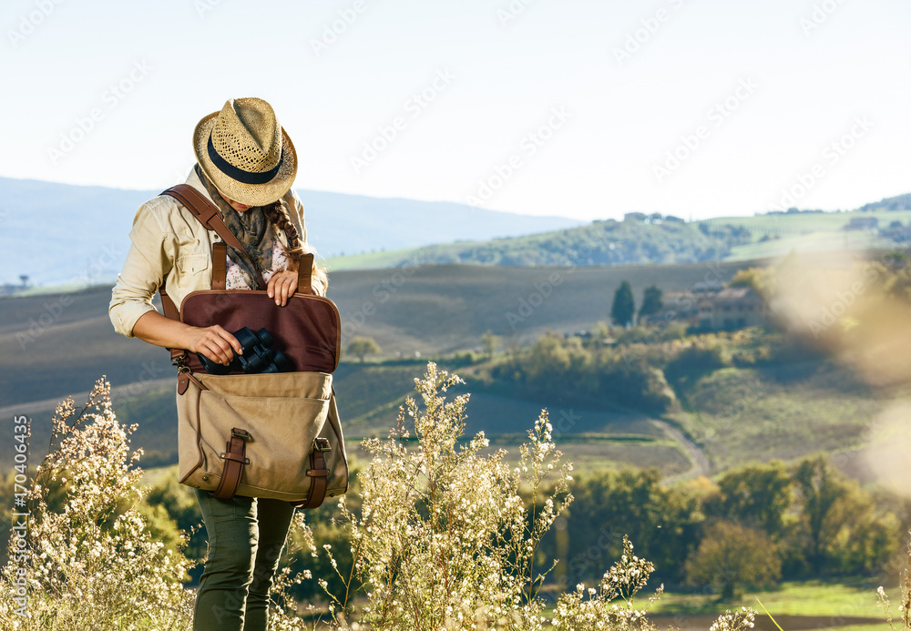 young woman hiker hiking in Tuscany taking binoculars