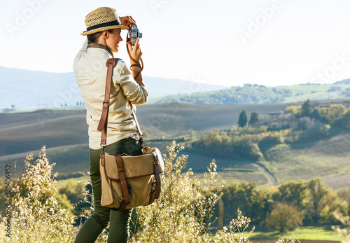 woman hiker in Tuscany taking photo with retro photo camera