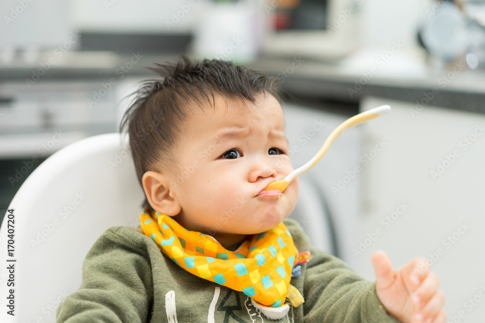 Asian baby boy eating blend food on a high chair Asian baby boy eating blend food on a high chair