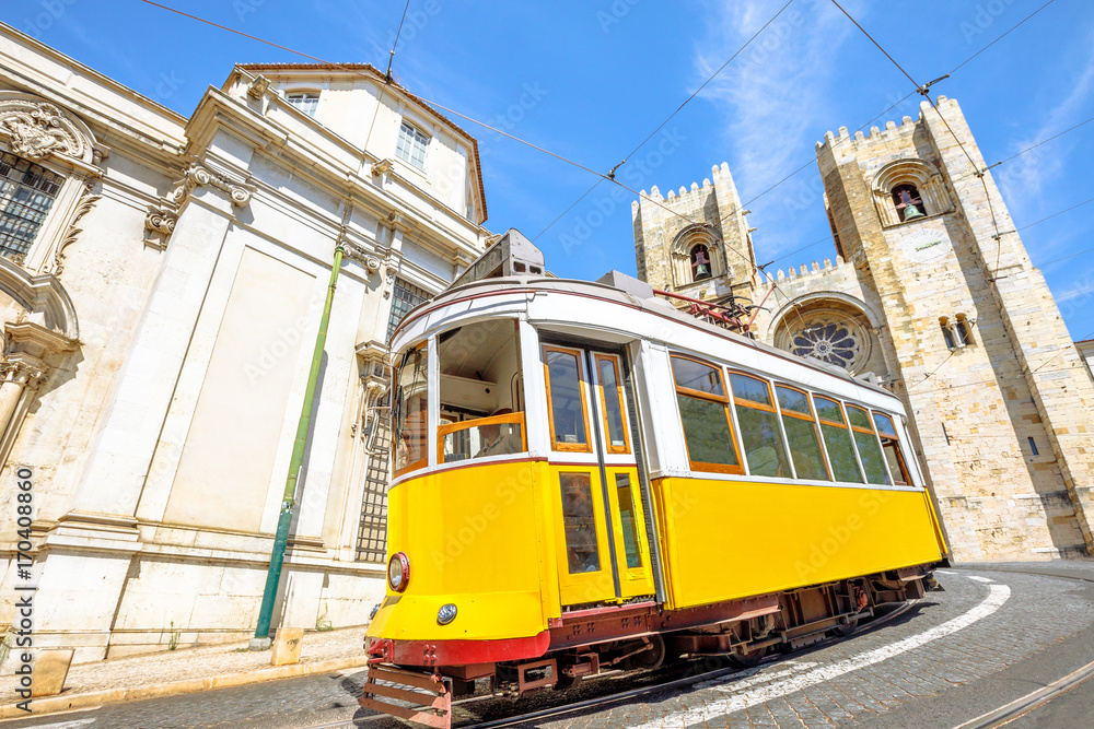Historic tram line in front of Lisbon Cathedral in Alfama district, Lisbon, Portugal. Lisbon street with typical yellow vintage tram and Se de Lisboa. Icons and symbols of the Portuguese capital.