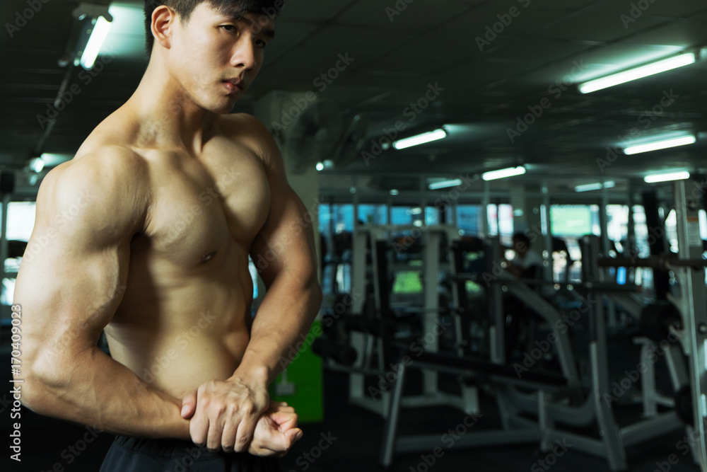 Fitness man showing muscular body in gym Fitness man showing muscular body in gym
