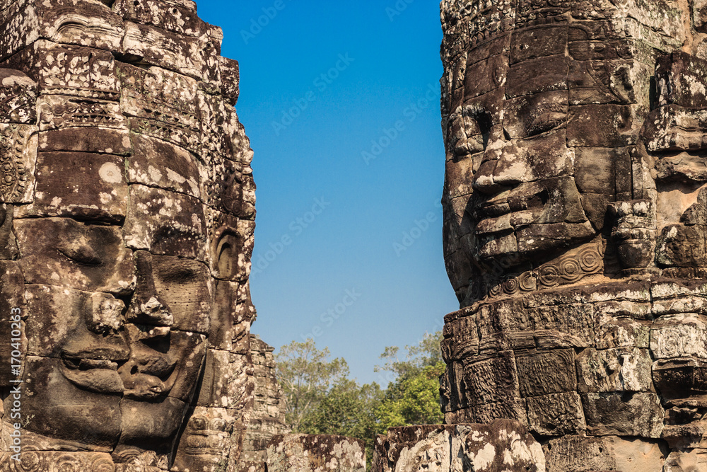 Ancient stone smiling faces of the Prasat Bayon Wat temple in the jungle, Angkor wat, Cambodia. Angkor Wat isthe largest religious monument in the world.