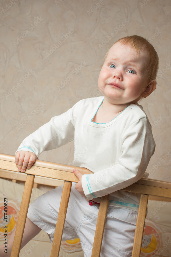 A child stands in the crib and crying A child stands in the crib and crying
