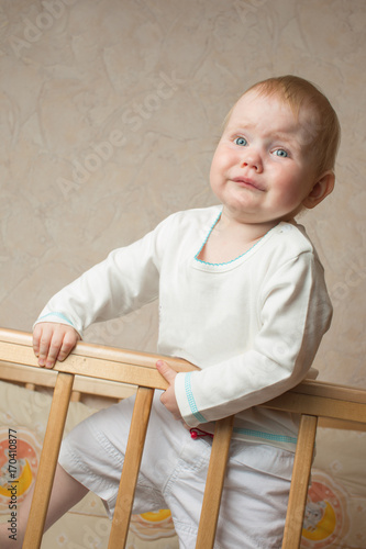 A child stands in the crib and crying