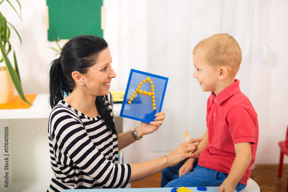 Little boy during lesson with his speech therapist. Learning through fun and play Little boy during lesson with his speech therapist. Learning through fun and play