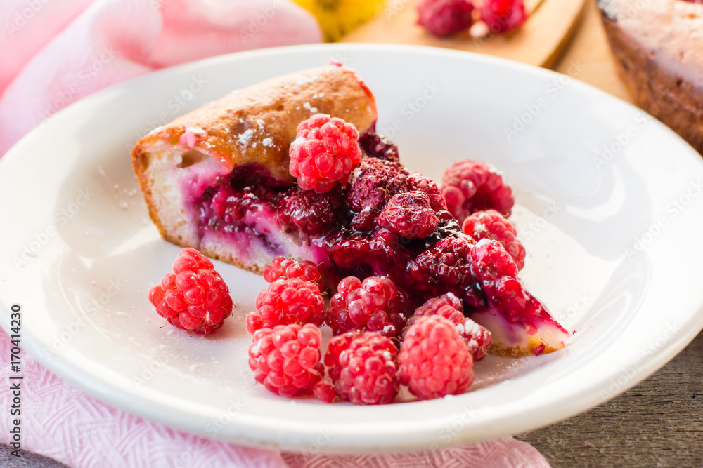 A piece of cake with raspberries and fresh berries on the plate A piece of cake with raspberries and fresh berries on the plate