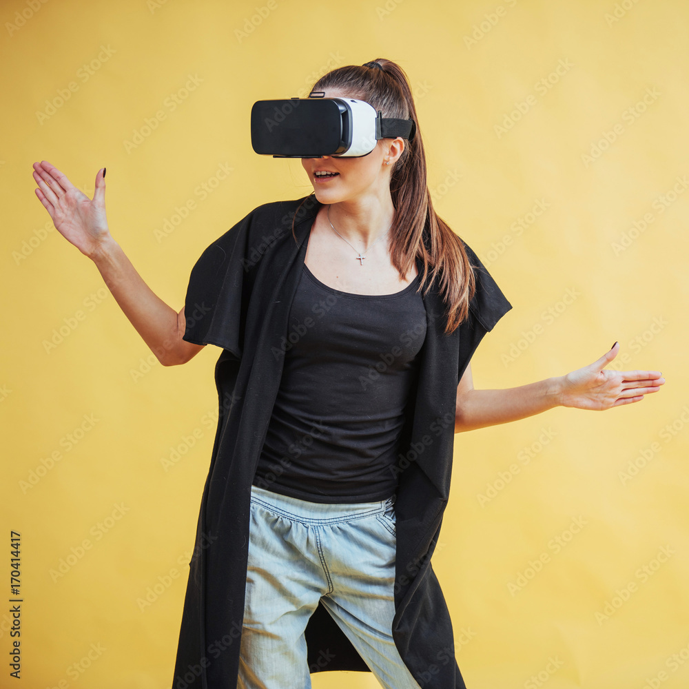 Happy woman on background in the studio gets the experience of using VR-glasses virtual reality headset Happy woman on background in the studio gets the experience of using VR-glasses virtual reality headset