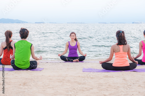 Yoga training class at sea beach in evening sunset ,Group of people doing lotus poses with clam relax emotion at beach,Meditation pose,Wellness and Healthy balance lifestyle