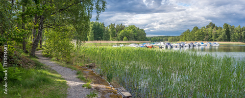 En vik på Värmdö med båtbryggor,  fritidsbåtar och en naturskön strandpromenad runt viken