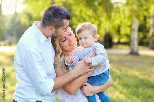 Happy family in a park in summer autumn. Mother, father and baby play in nature in the rays of sunset. © Studio Romantic