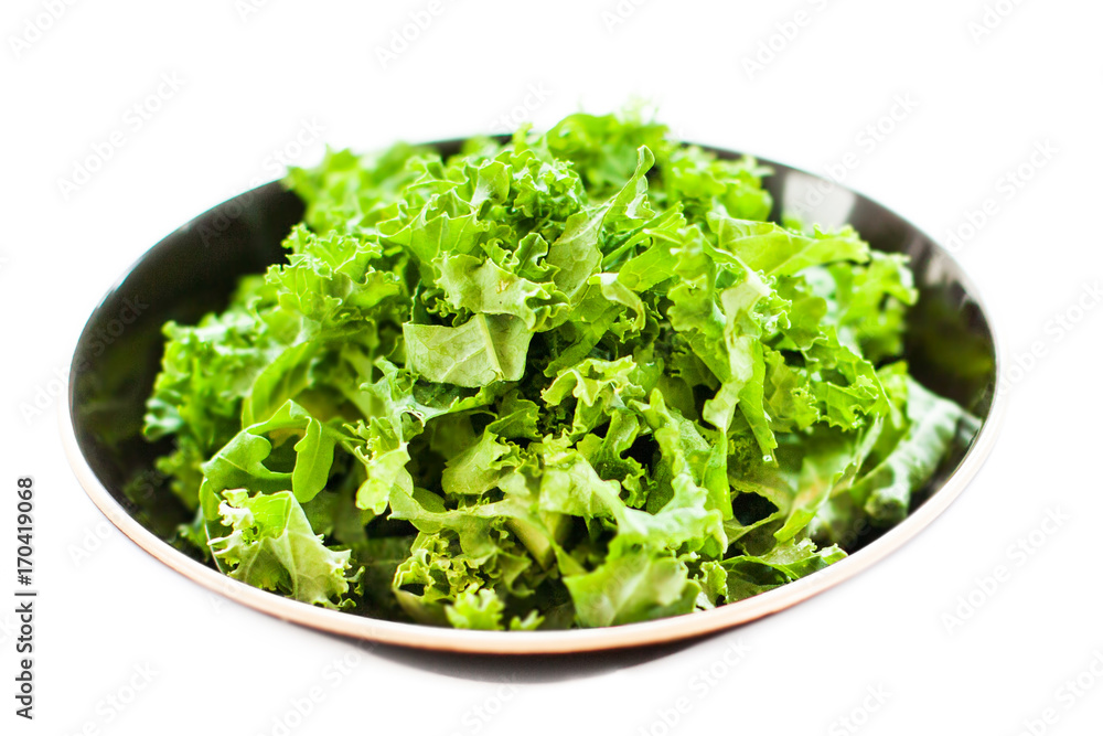 Fresh green kale salad leaves in a bowl isolated on white with copy space for text background. Fresh green kale salad leaves in a bowl isolated on white with copy space for text background.