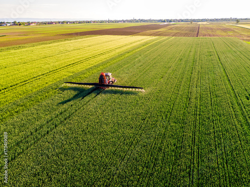 Farmer spraying green wheat field photo