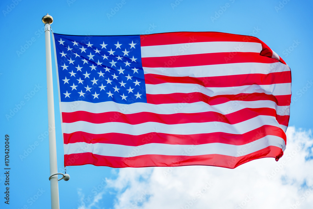 American US flag on a pole against blue sky American US flag on a pole against blue sky