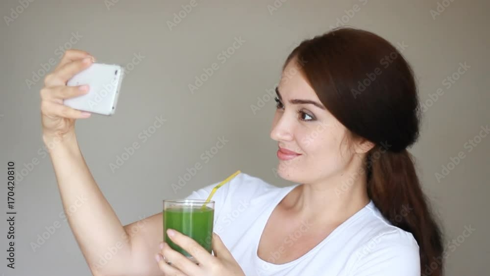 Young woman drink smoothie and smiling and making selfies on the phone or smartphone. Young woman drink smoothie and smiling and making selfies on the phone or smartphone.