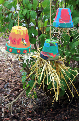 three colorful flower pots filled with straw hanging upside-down photo