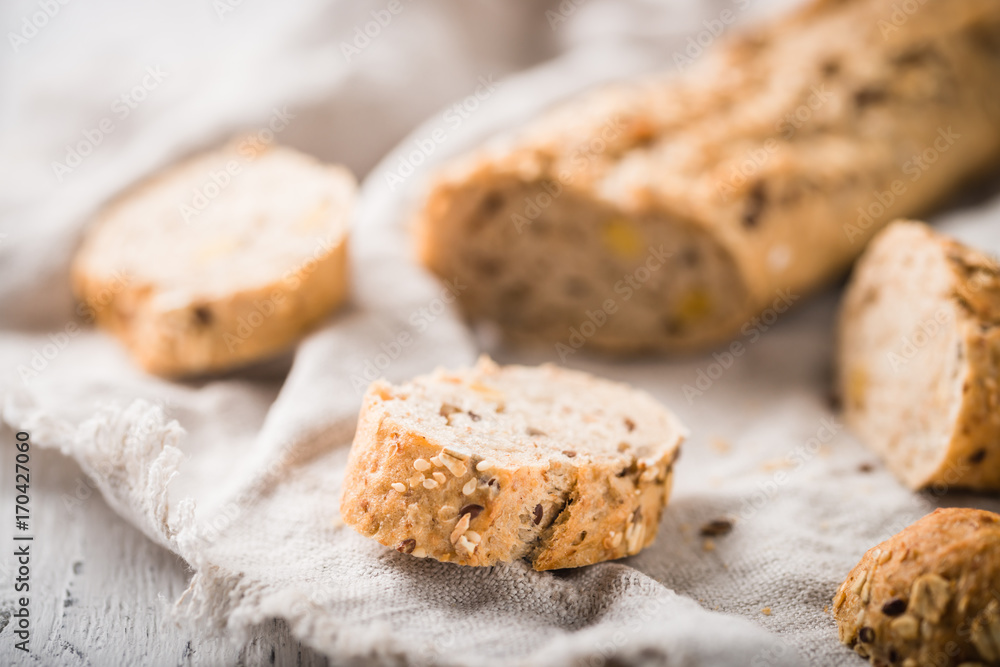 Fresh, healthy whole grain rye baguette with slices on cloth and rustic wooden table, close up. Bakery and grocery concept Fresh, healthy whole grain rye baguette with slices on cloth and rustic wooden table, close up. Bakery and grocery concept
