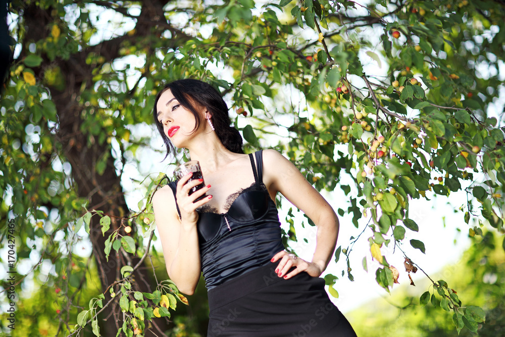 Красивая девушка с бокалом вина в руках на природе