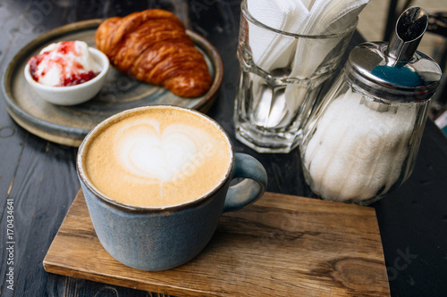 Coffee, croissant and ice-cream with strawberry jam on stone plate on black wooden table. Tasty background.