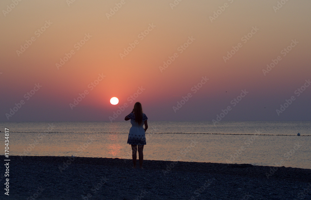 Fototapeta premium Junge Frau blickt dem Sonnenaufgang entgegen