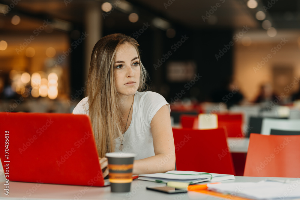 pretty female student with laptop  and coffee learning in a high school library