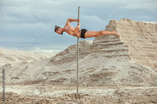 Athlete acrobat.Male Athlete acrobat doing acrobatic stunts on the pole.