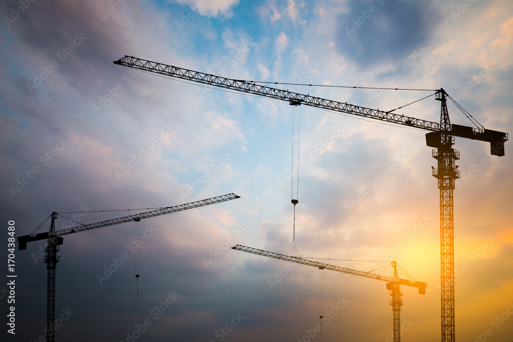 Abstract Industrial background with construction cranes silhouettes over amazing sunset sky