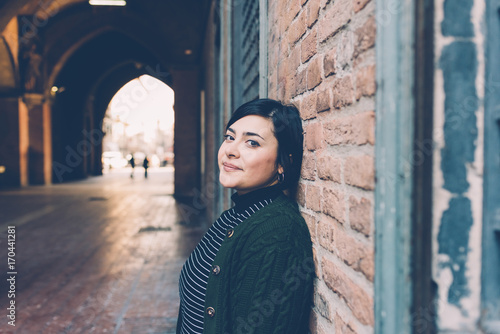 Portrait of young woman looking over smiling leaning brick wall - curvy, happiness, different beauty concept © Eugenio Marongiu