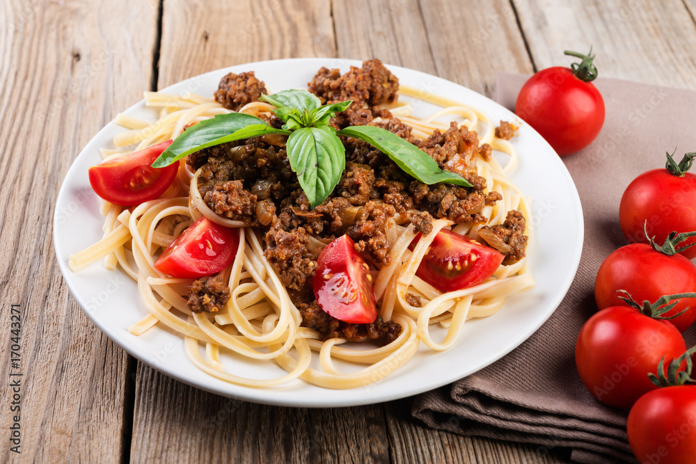 Italian spaghetti   with bolognese sauce, meat, cheese and fresh tomatoes and  basil - homemade healthy italian pasta on rustic wooden background.