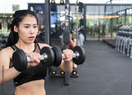 young woman execute exercise in fitness center. female athlete lift dumbbell in gym. sporty girl working out in health club.