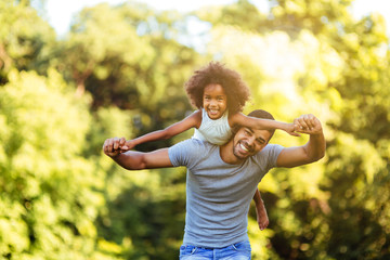 Portrait of young father carrying his daughter on his back