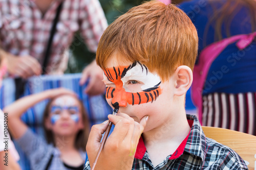 Child boy face painting, making tiger eyes process