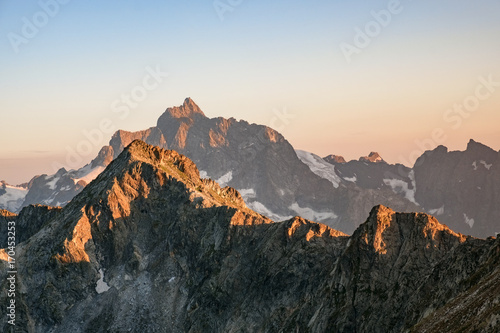 mountain peaks with snow at sunset, sunrise on sky background © Ambartsumian