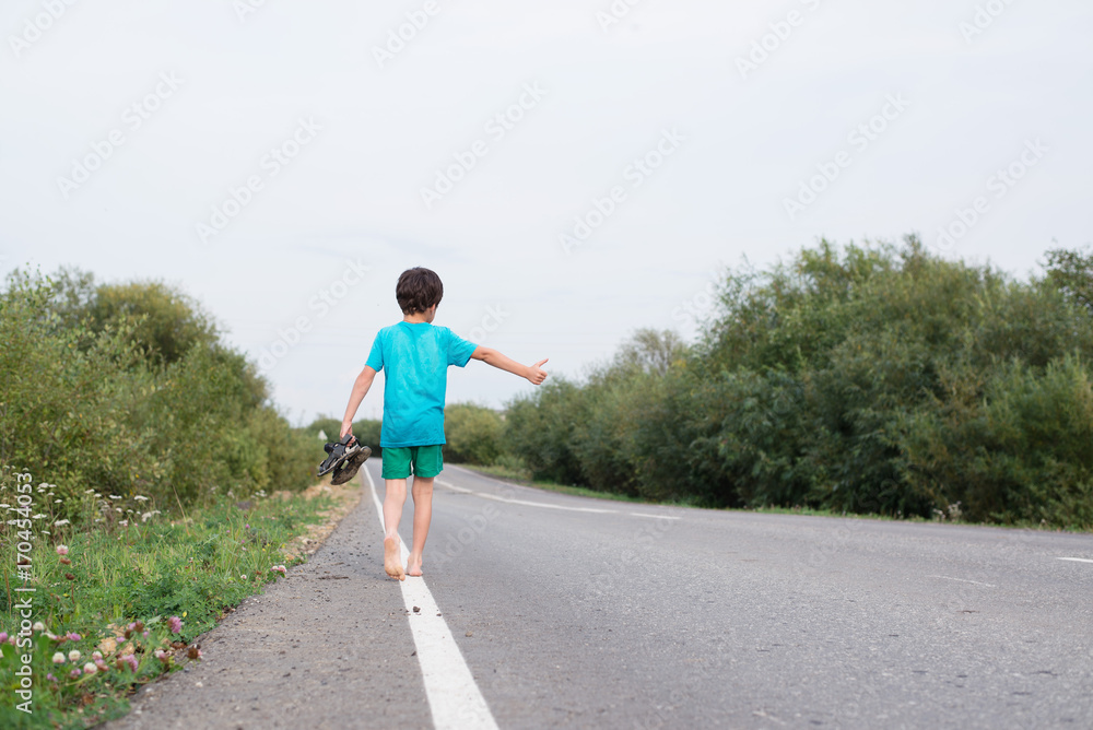 Obraz premium the boy walks barefoot along the road