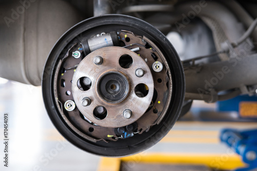 car suspension & bearing of wheel hub in auto service maintenance. Car lift up by hydraulic, waiting for tire replacement in garage. punched wheel concept