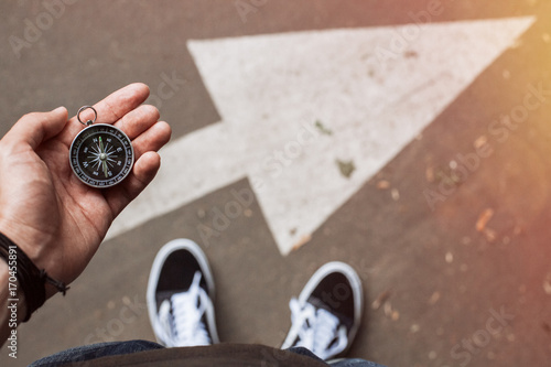 Hipster traveler holding compass in the hand making choice in what direction to go photo