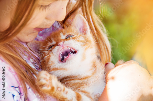 Little girl with a red kitten in hands close up.  Bestfriends. Interaction of children with pets.