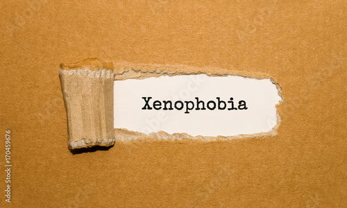 Photos The text Xenophobia appearing behind torn brown paper