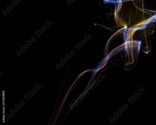 multicolored smoke dissipates in the air on an isolated black background