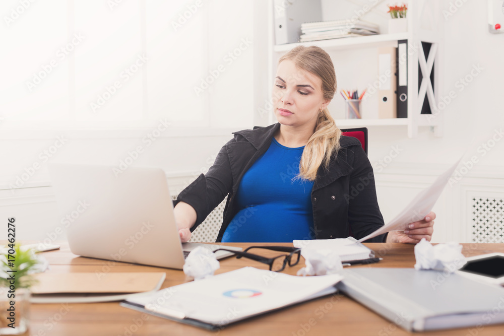 Pregnant business lady at work reading papers Pregnant business lady at work reading papers