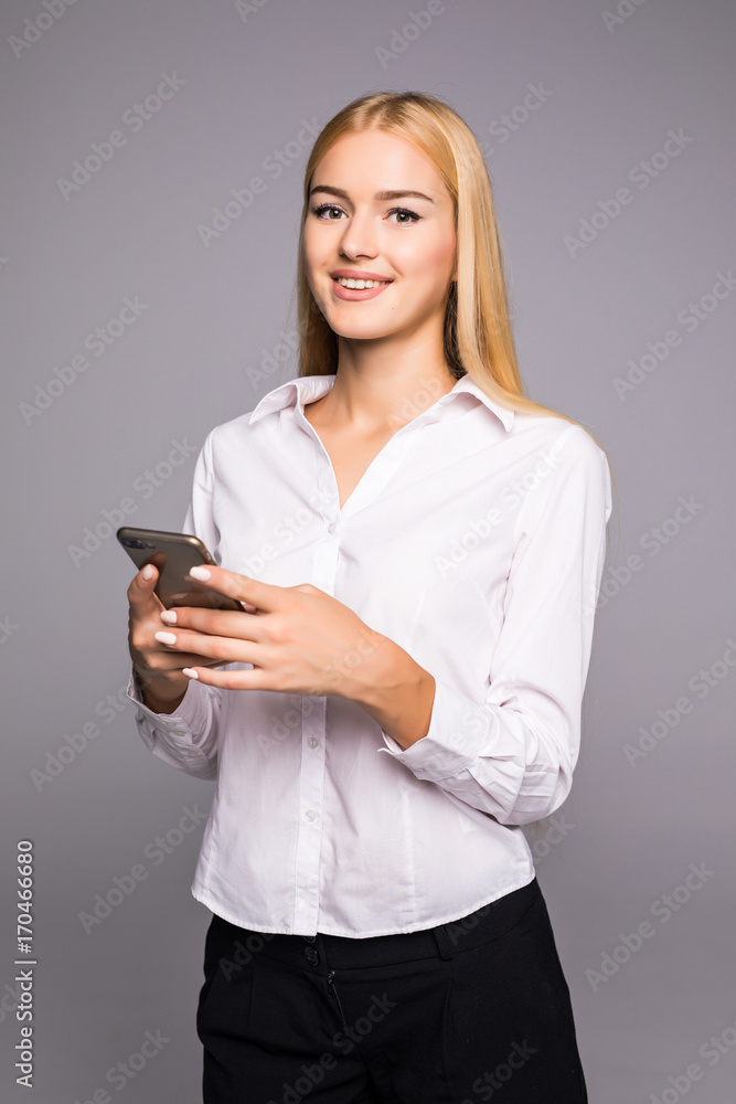 Young woman typing message on smartphone. beautiful smiling girl using his mobile phone, gray studio background. Communication concept Young woman typing message on smartphone. beautiful smiling girl using his mobile phone, gray studio background. Communication concept