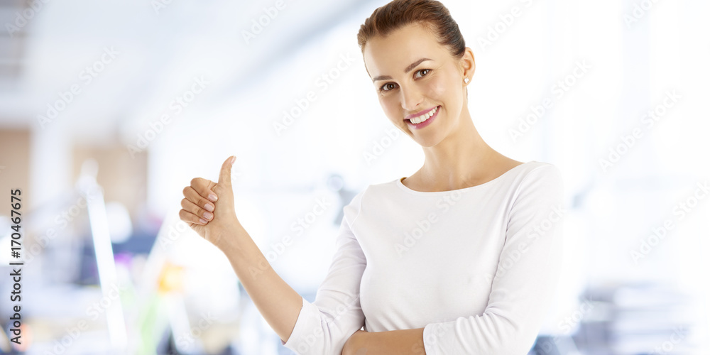 Successful young woman giving thumbs up while looking at camera and smiling. Successful young woman giving thumbs up while looking at camera and smiling.