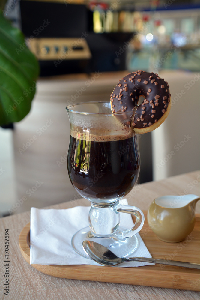 Black coffee with milk in a glass cup on a wooden table Black coffee with milk in a glass cup on a wooden table