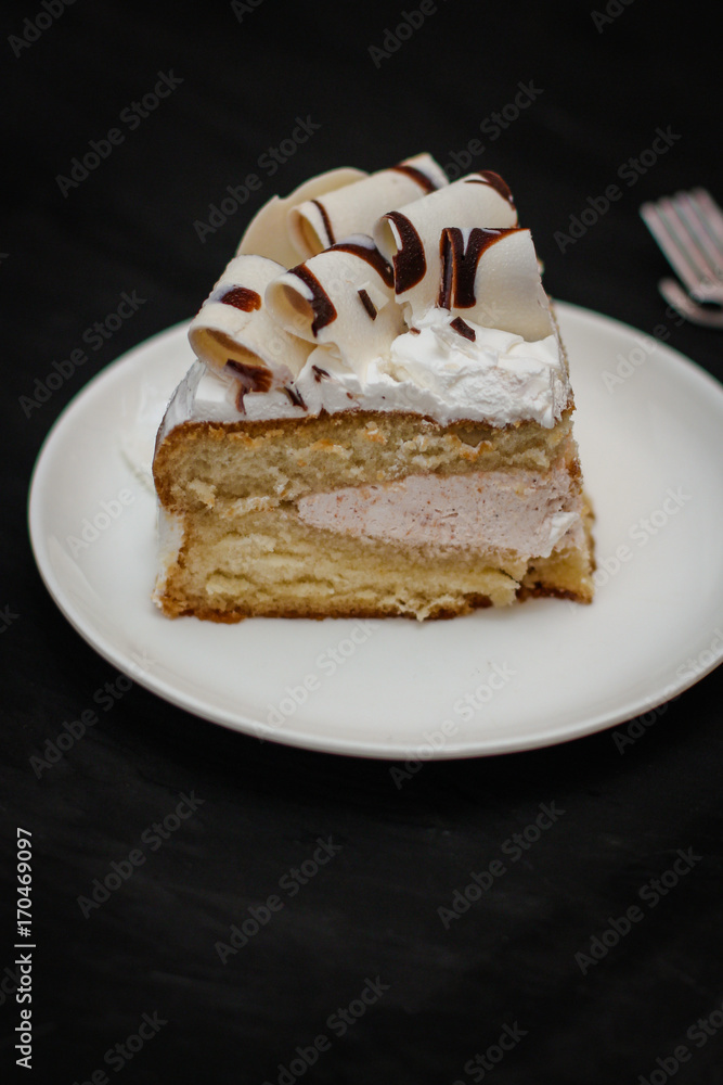 piece of cake in a white plate on a black background